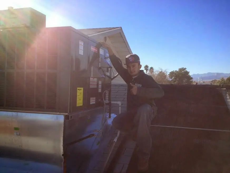 HVAC technician performing AC Tune-Up on a rooftop unit in Plainville
